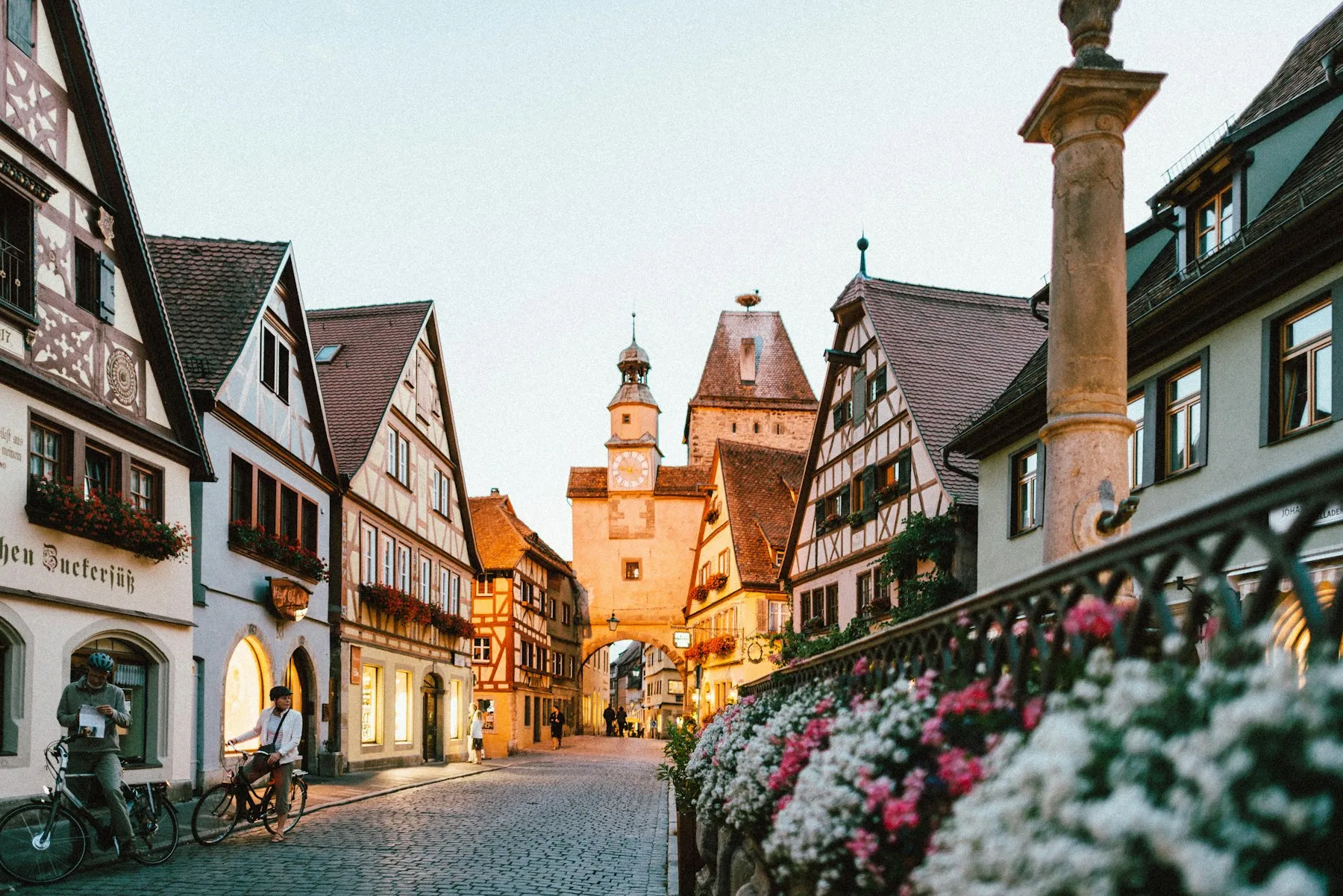 Cobblestone street lined with traditional half-timbered houses and a clock tower in a historic German old town